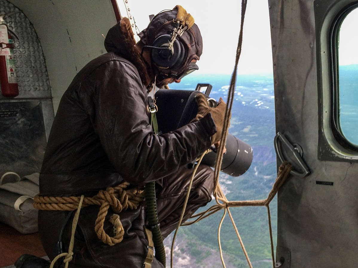 Melalui pintu terbuka sebuah pesawat, Brad Washburn menangkap gambar ikonik, berpartisipasi dalam eksplorasi pertama di Alaska, wilayah yang kemudian tidak dikenal.